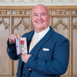 A picture of Aquatics GB swimming coach David McNulty holding his MBE at Windsor Castle following his investiture in December 2024